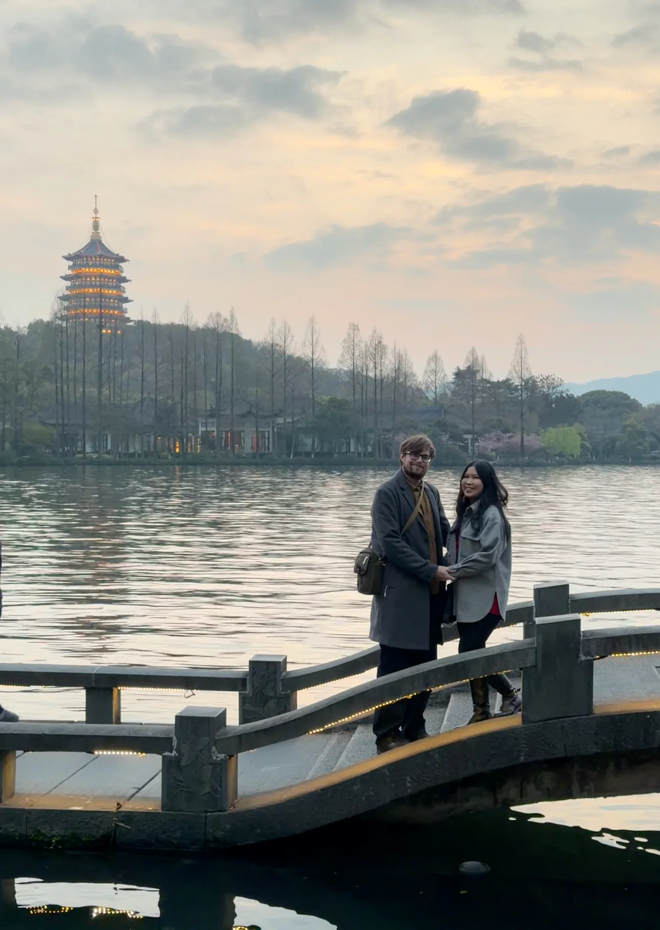 Lewis and Gail holding hands beside a lake at dusk.