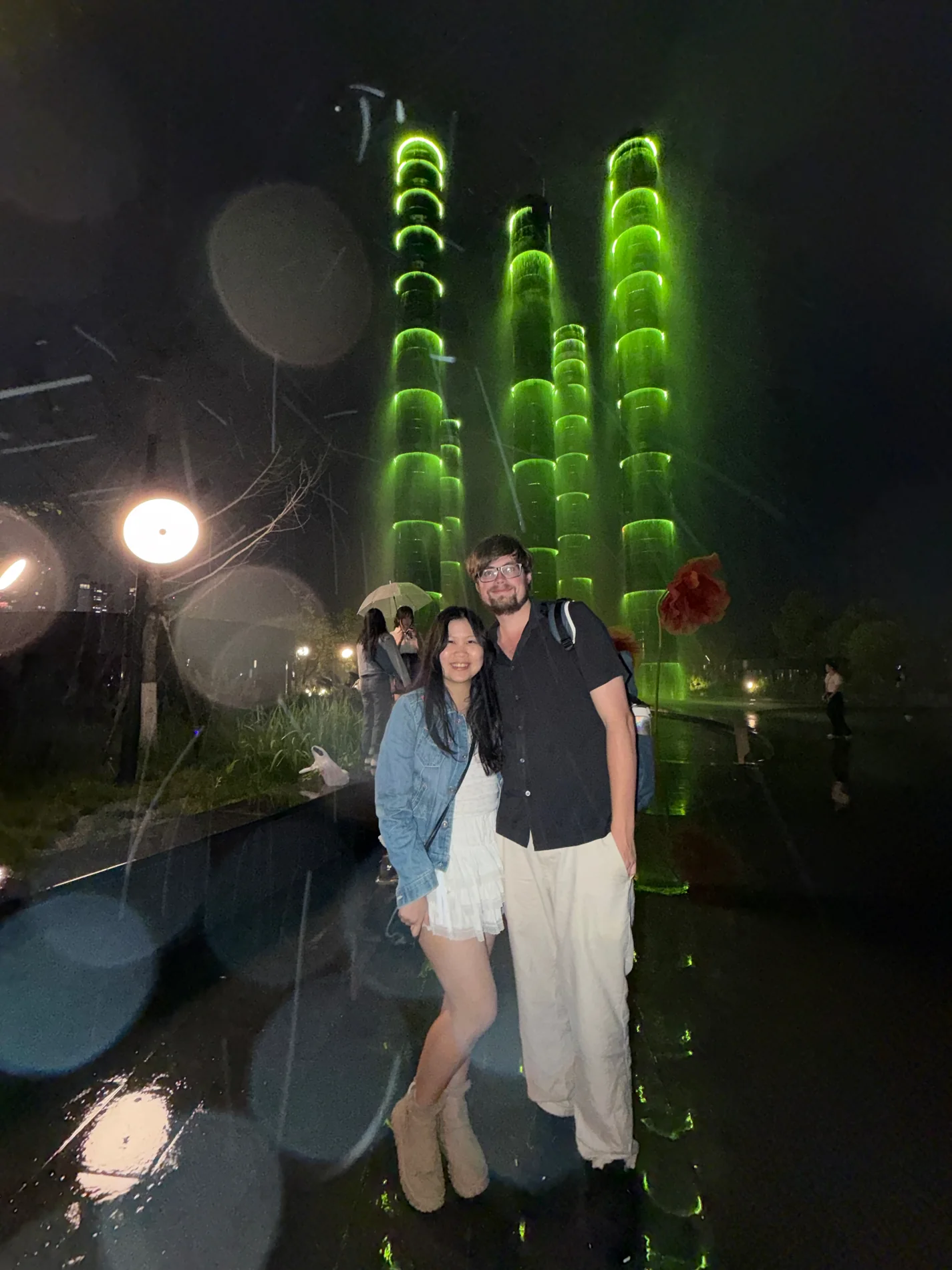 Lewis and Gail standing together under glowing green lights at night.