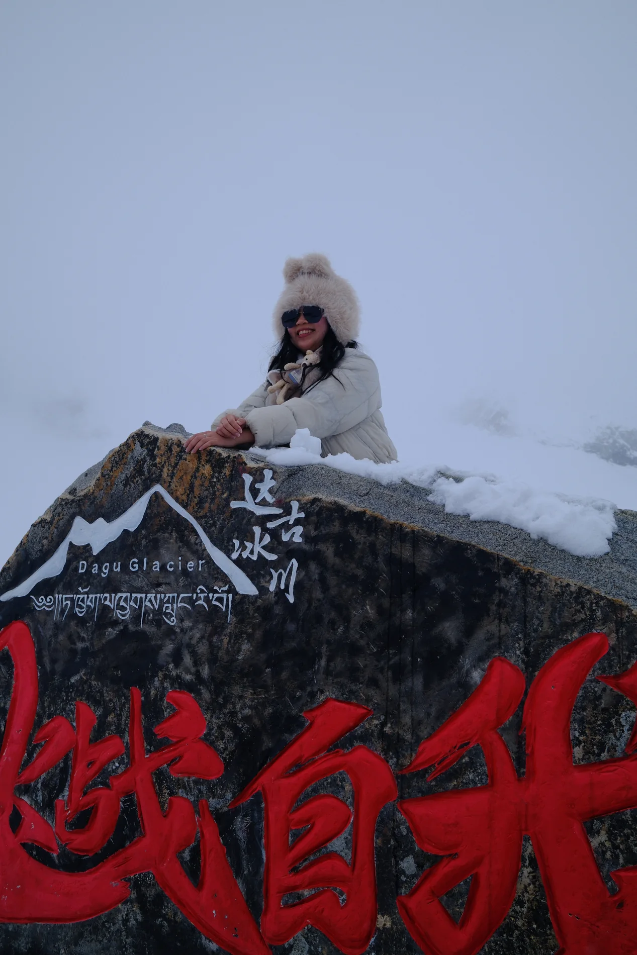 Gail bundled up beside a snow-covered handwritten sign.