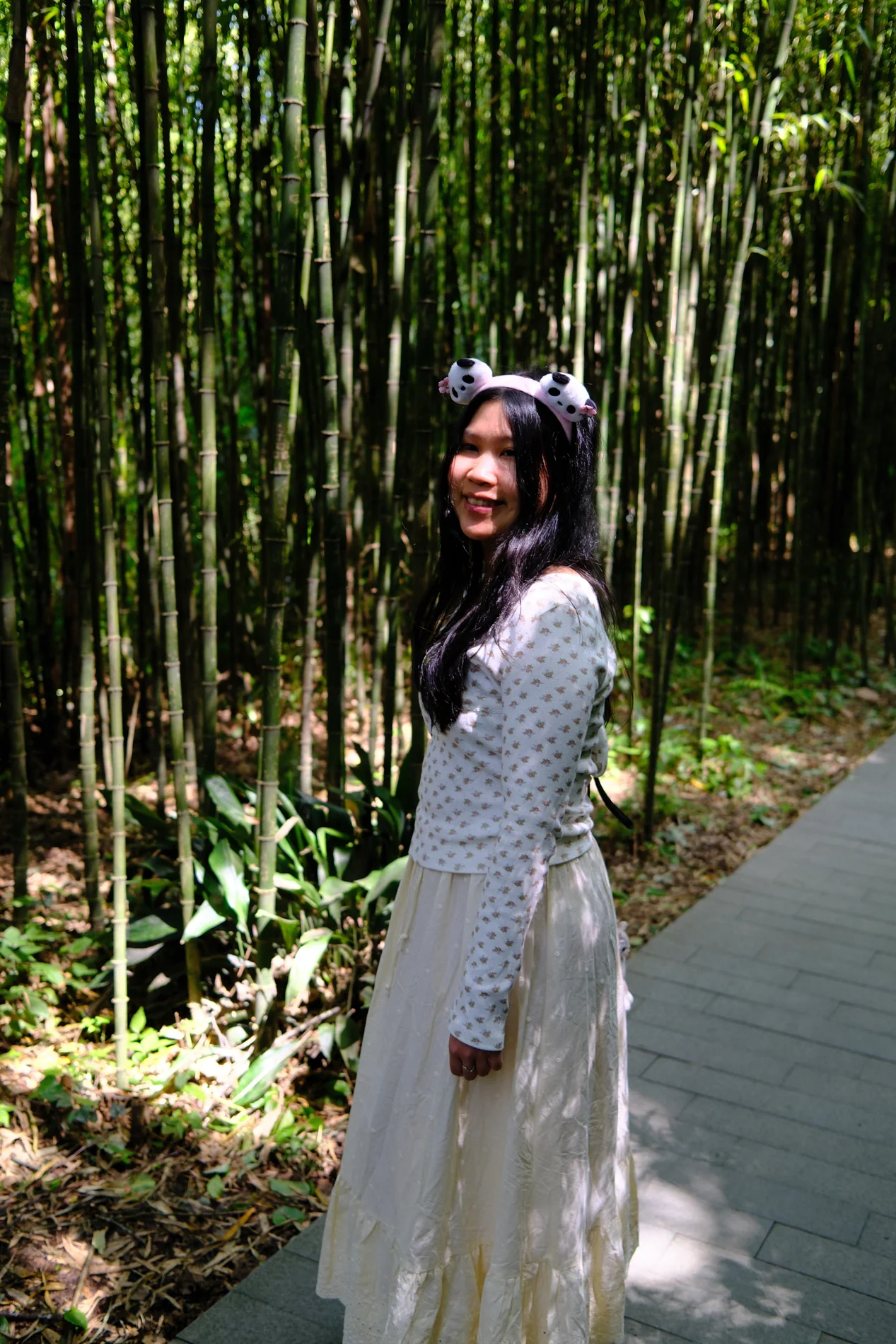 Gail smiling along a sunlit path through bamboo.