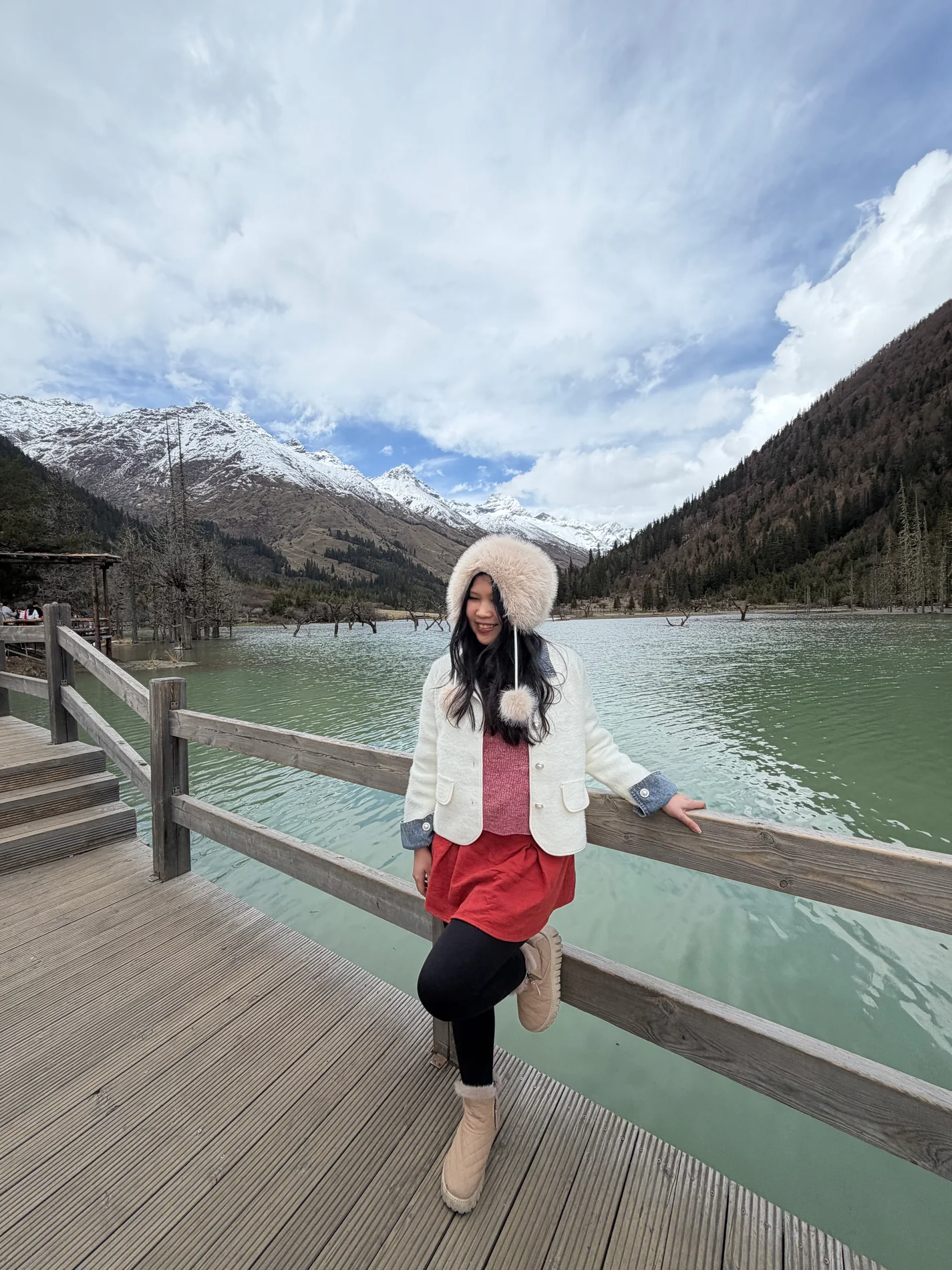 Gail standing beside a turquoise mountain lake in the snow.