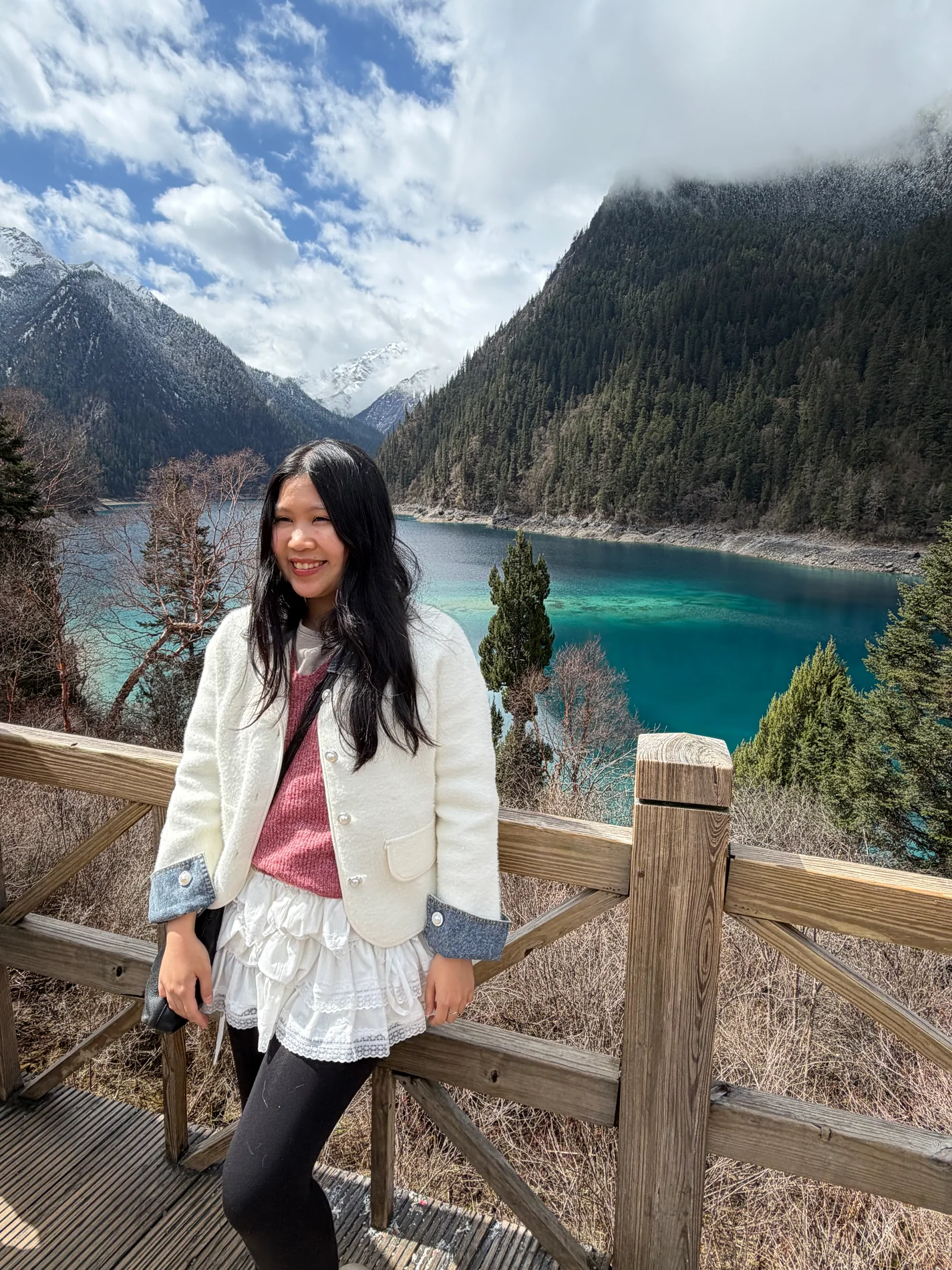 Gail smiling at a mountain overlook above a blue lake.