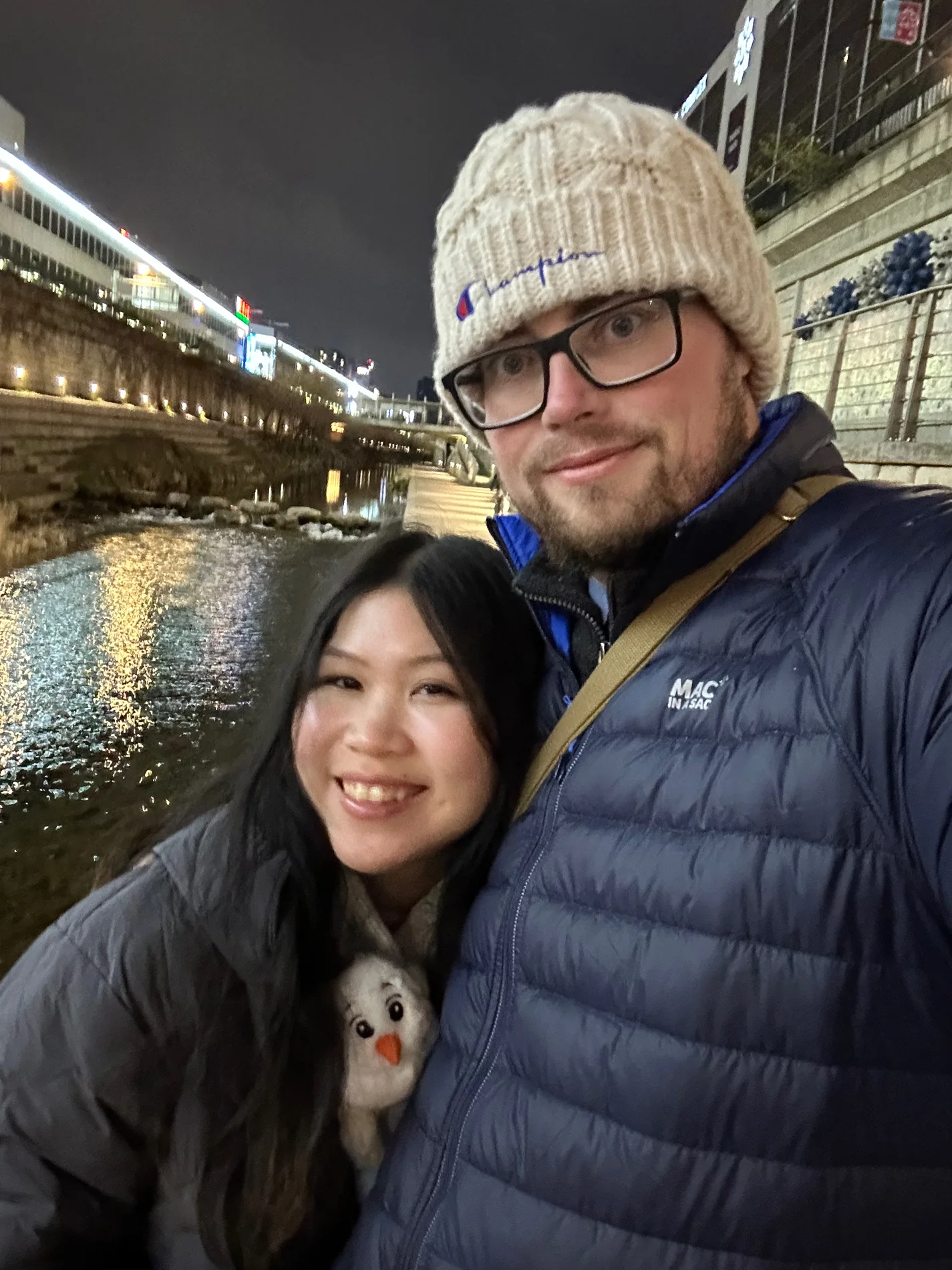 Lewis and Gail taking a cosy winter selfie beside a stream.