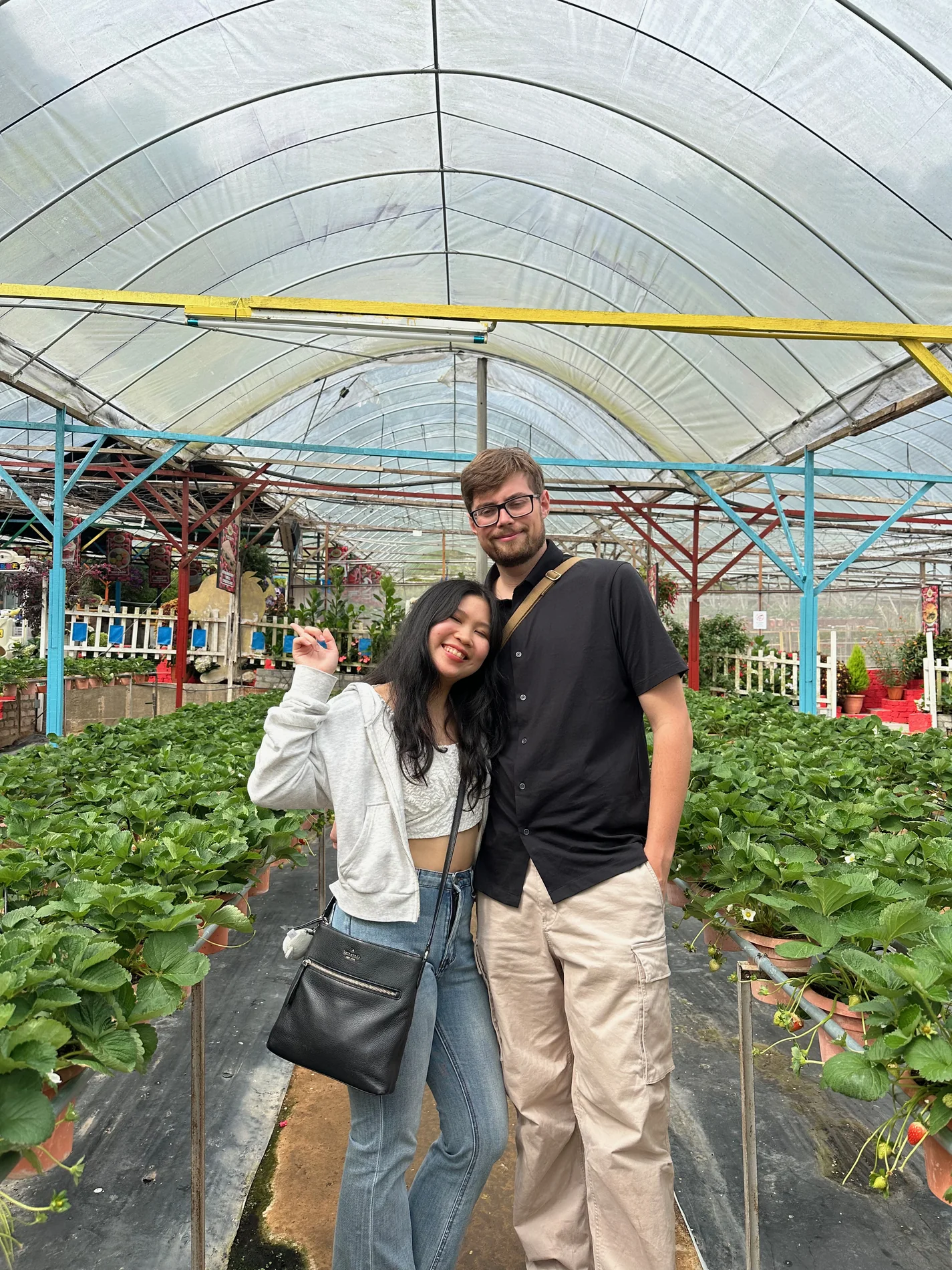 Lewis and Gail standing close together in a strawberry greenhouse.