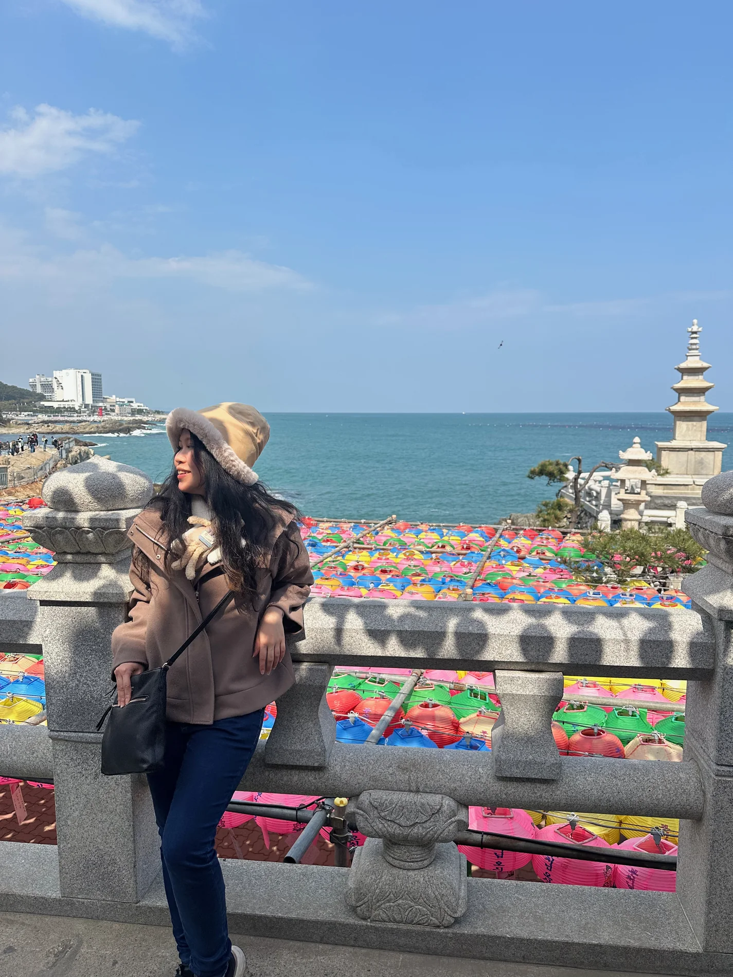 Gail looking out over a bright coastline and temple.