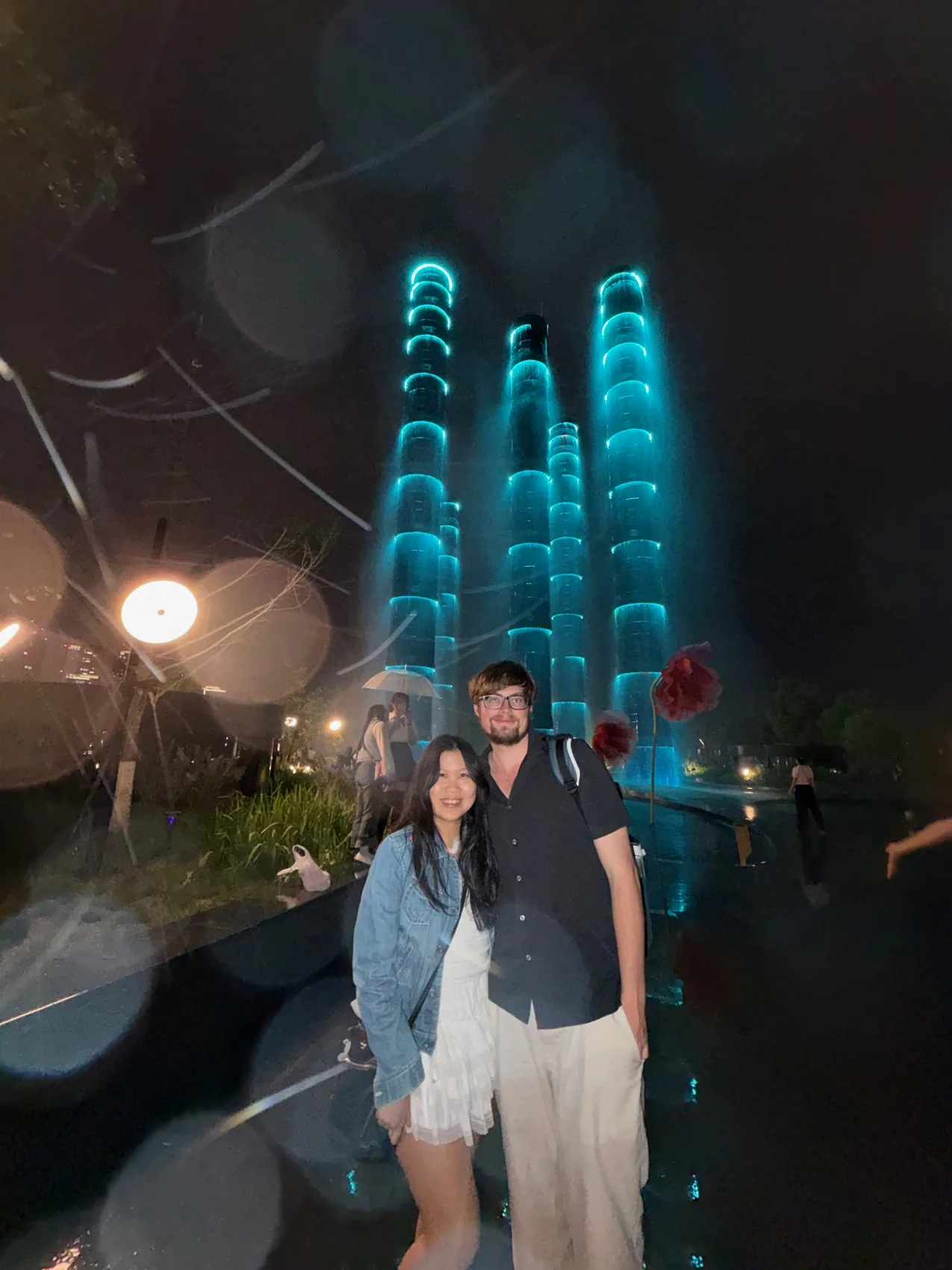 Lewis and Gail standing together beneath blue lights at night.