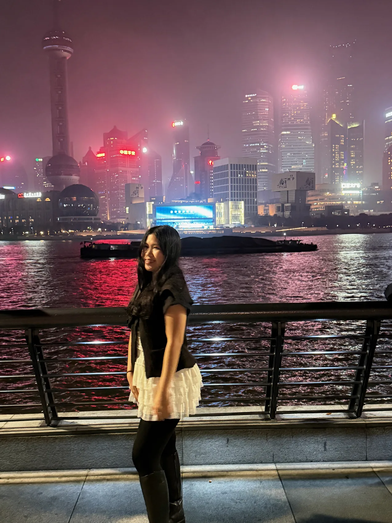 Gail smiling beside a city skyline at night.