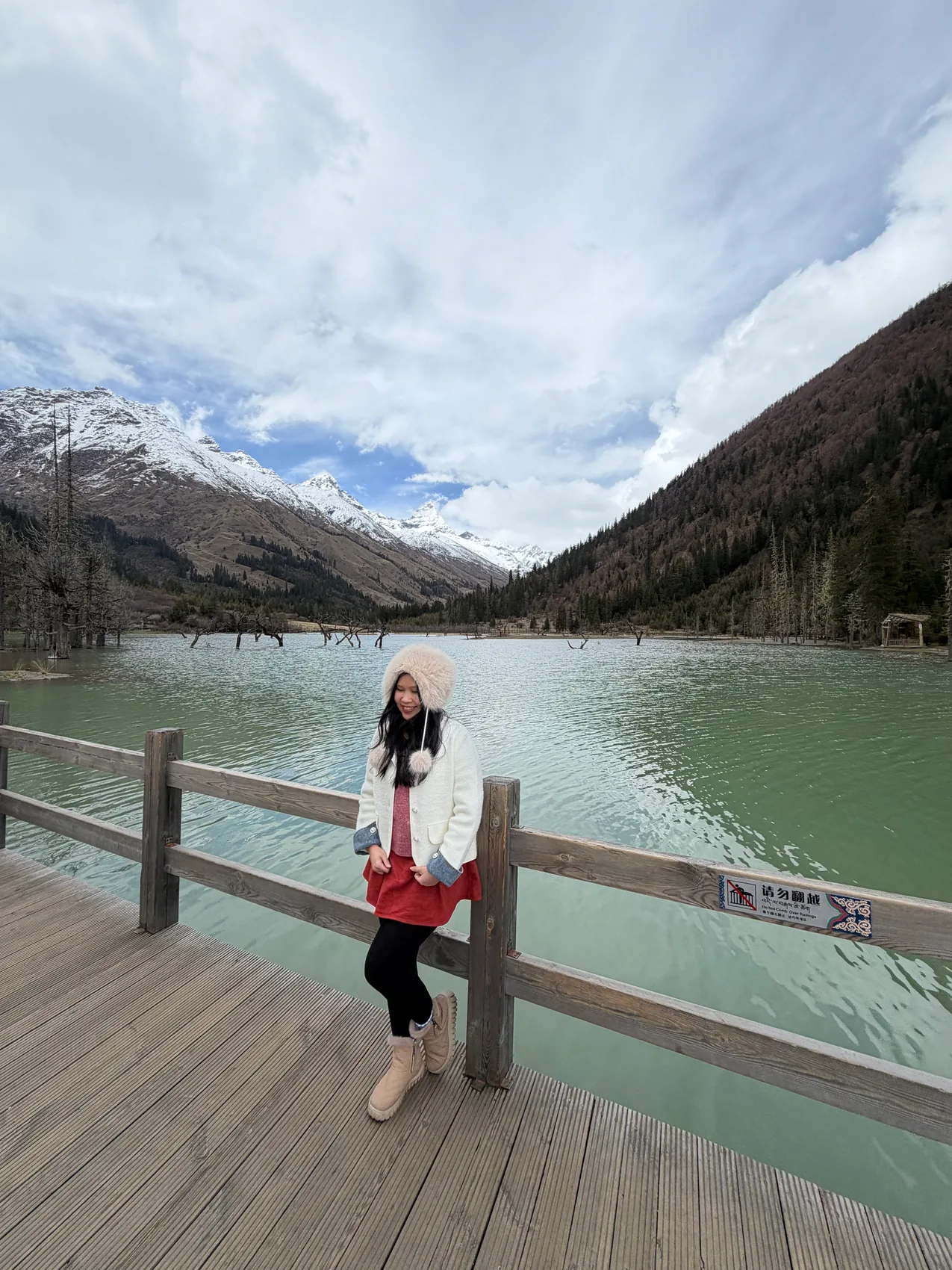 Gail smiling beside a bright mountain lake.