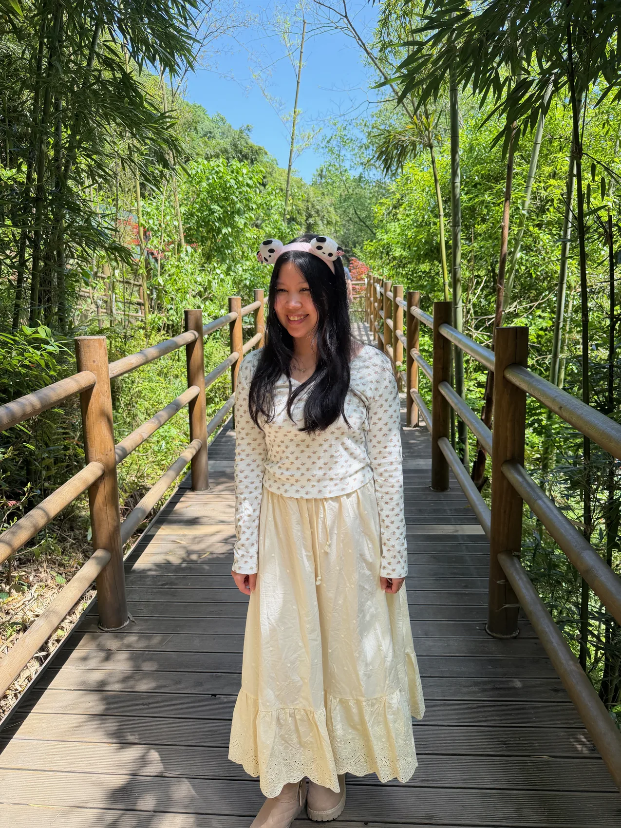 Gail smiling on a wooden path through bamboo.