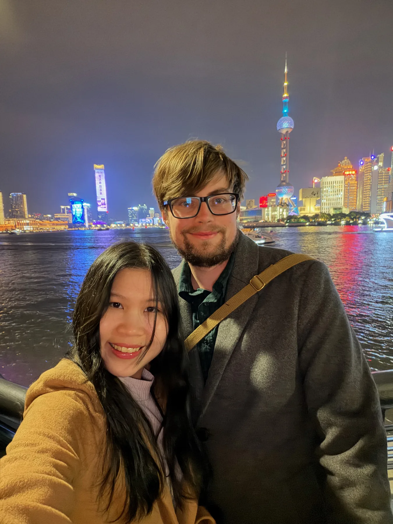 Lewis and Gail taking an evening selfie beside a lit city skyline.