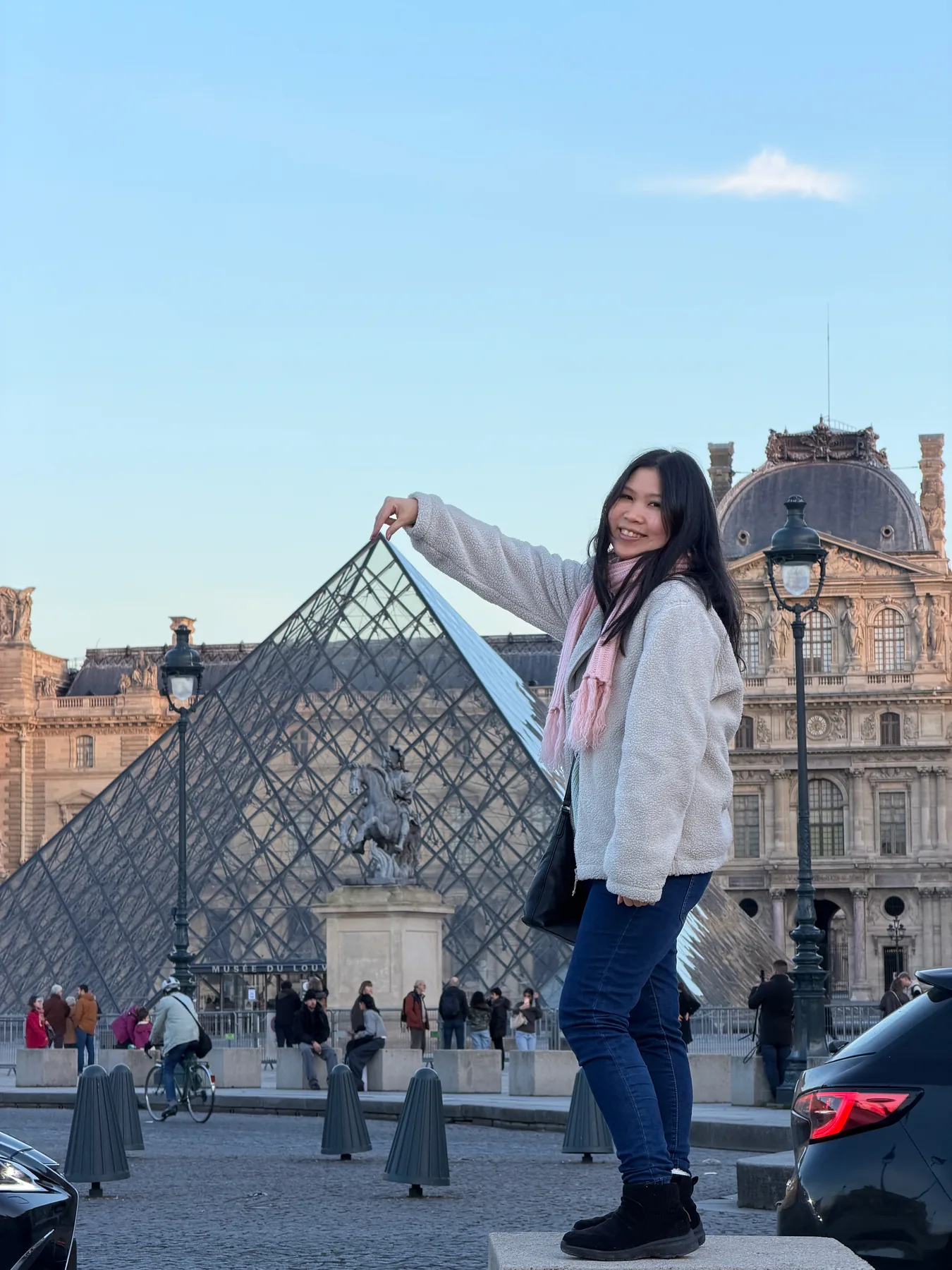 Gail playfully pointing toward the glass pyramid outside the Louvre.
