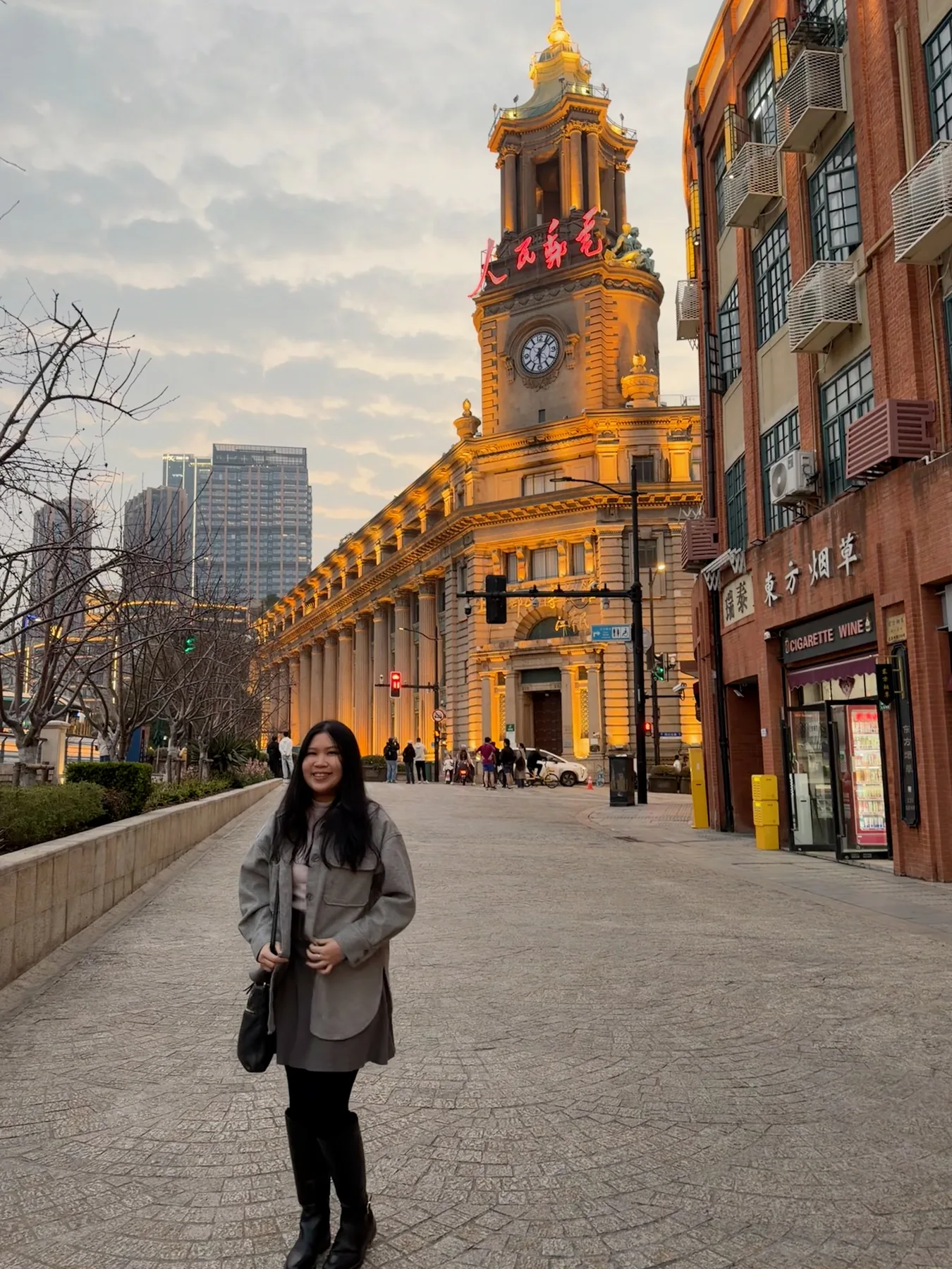 Gail standing on a city street beside a warmly lit clock tower.